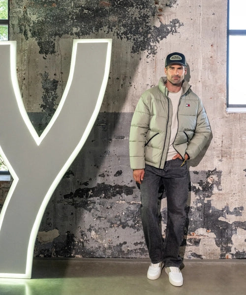 Das Model trägt ein olivfarbenes Outfit.