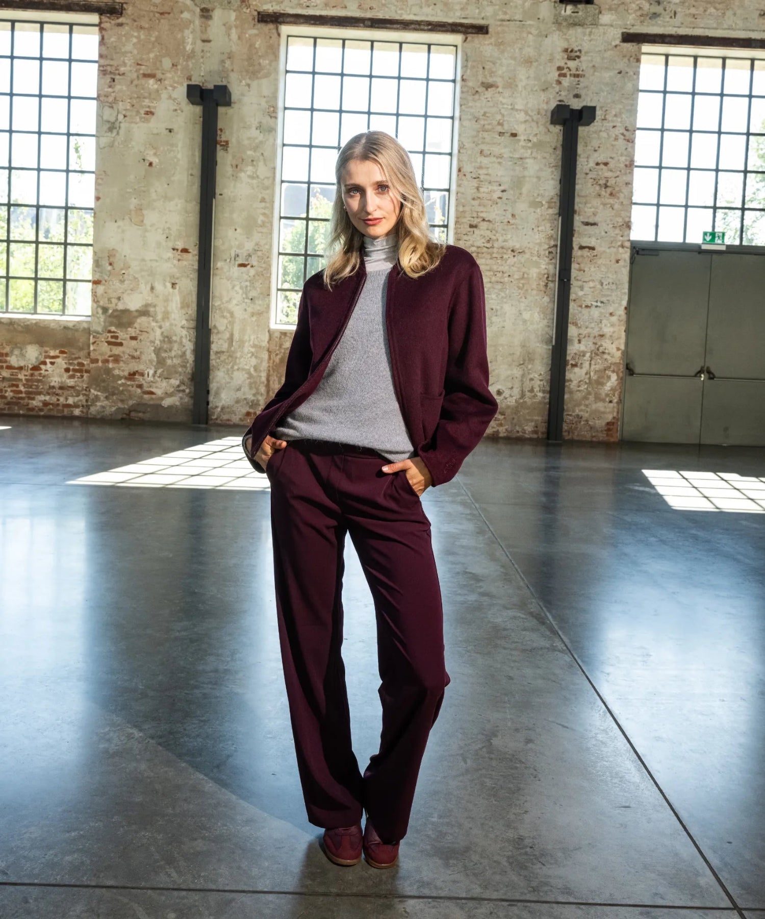 Das Model trägt einen bordeauxfarben Anzug.