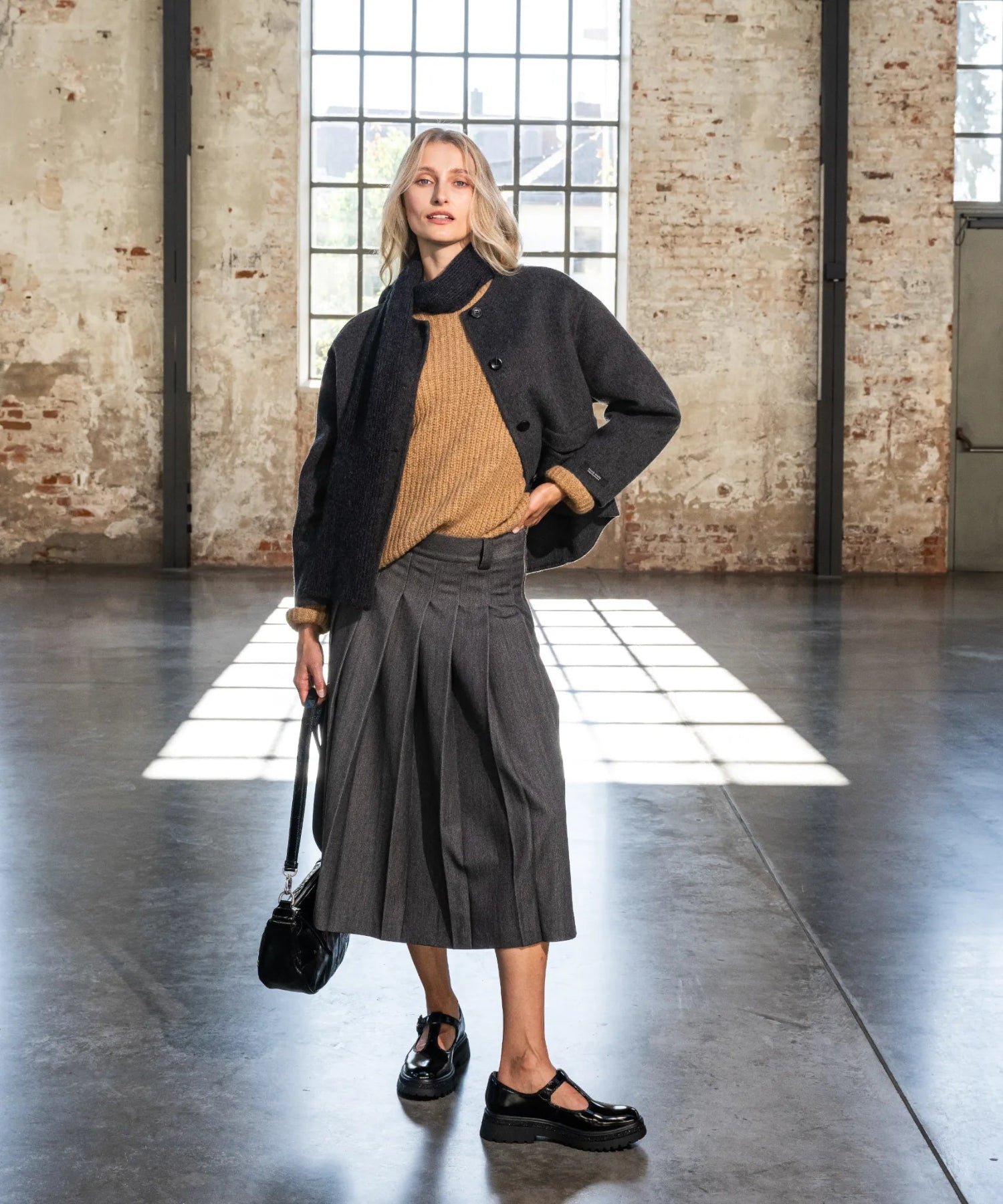 Das Model trägt grauen Faltenrock.