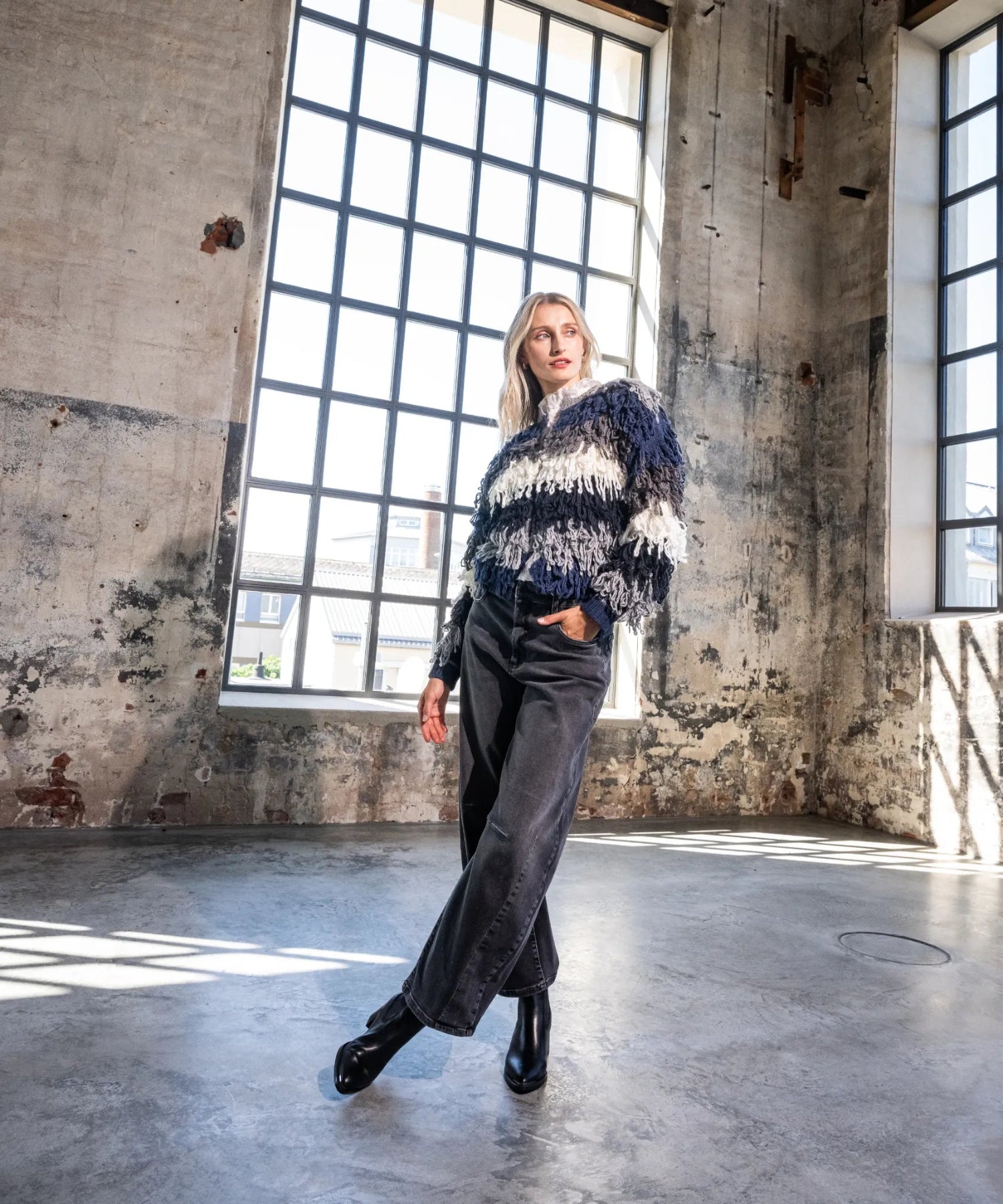 Das Model trägt modischen Fransensweater.