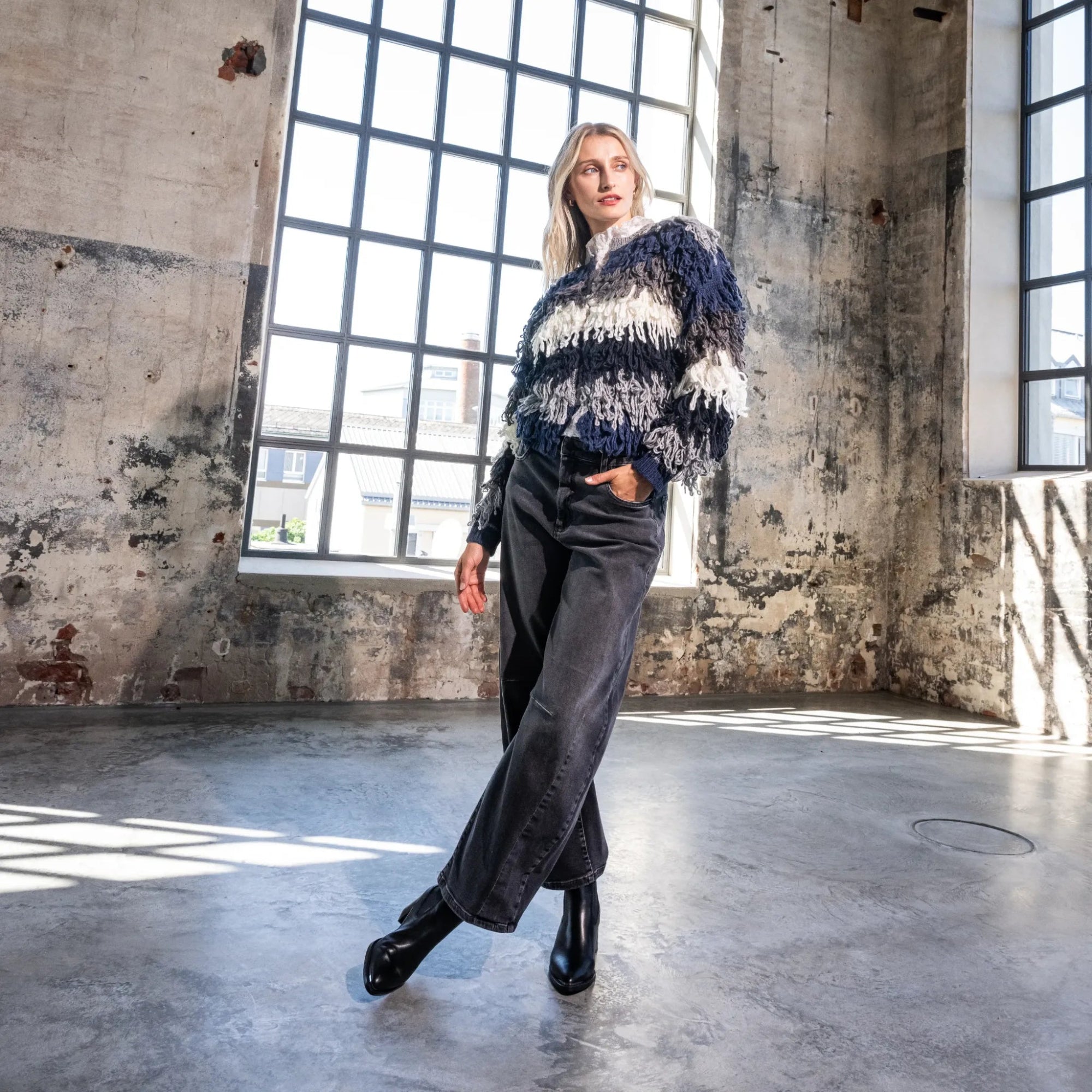 Das Model trägt modischen Fransensweater.