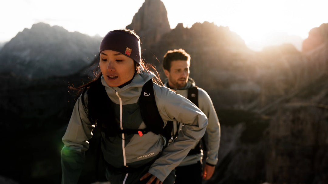 Zwei Menschen wandern auf einen Berg bei Sonnenaufgang.