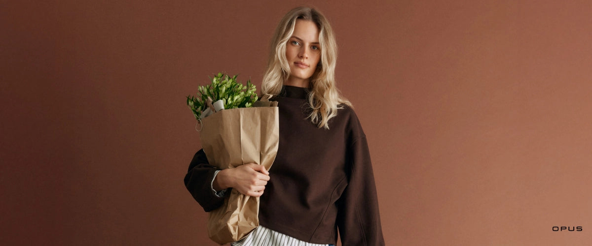 OPUS Damenmode Kampagnenbild mit Frau in modernen Herbstoutfits vor einfarbigem Hintergrund