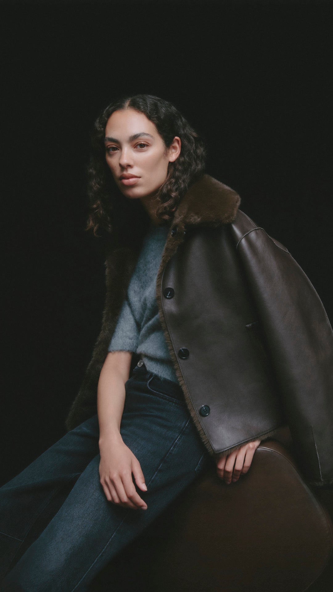 OPUS Cape-Jacke aus Lederoptik mit Fellkragen über grauem Strickpullover und dunkler Jeans bei FREY Mode